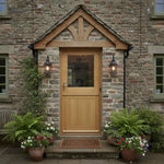 Wooden door with glass panels on a stone building, surrounded by potted plants.
