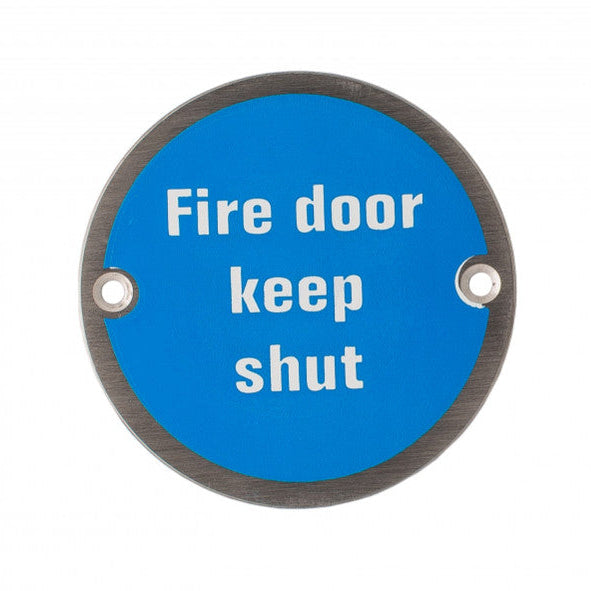 Product A round blue fire door keep shut sign with white text and a dark metal border, shown on a plain white background.