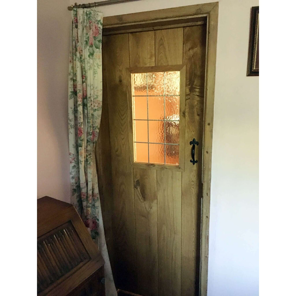 Lifestyle solid oak three-ledge unglazed rustic V-groove cottage door in an interior setting