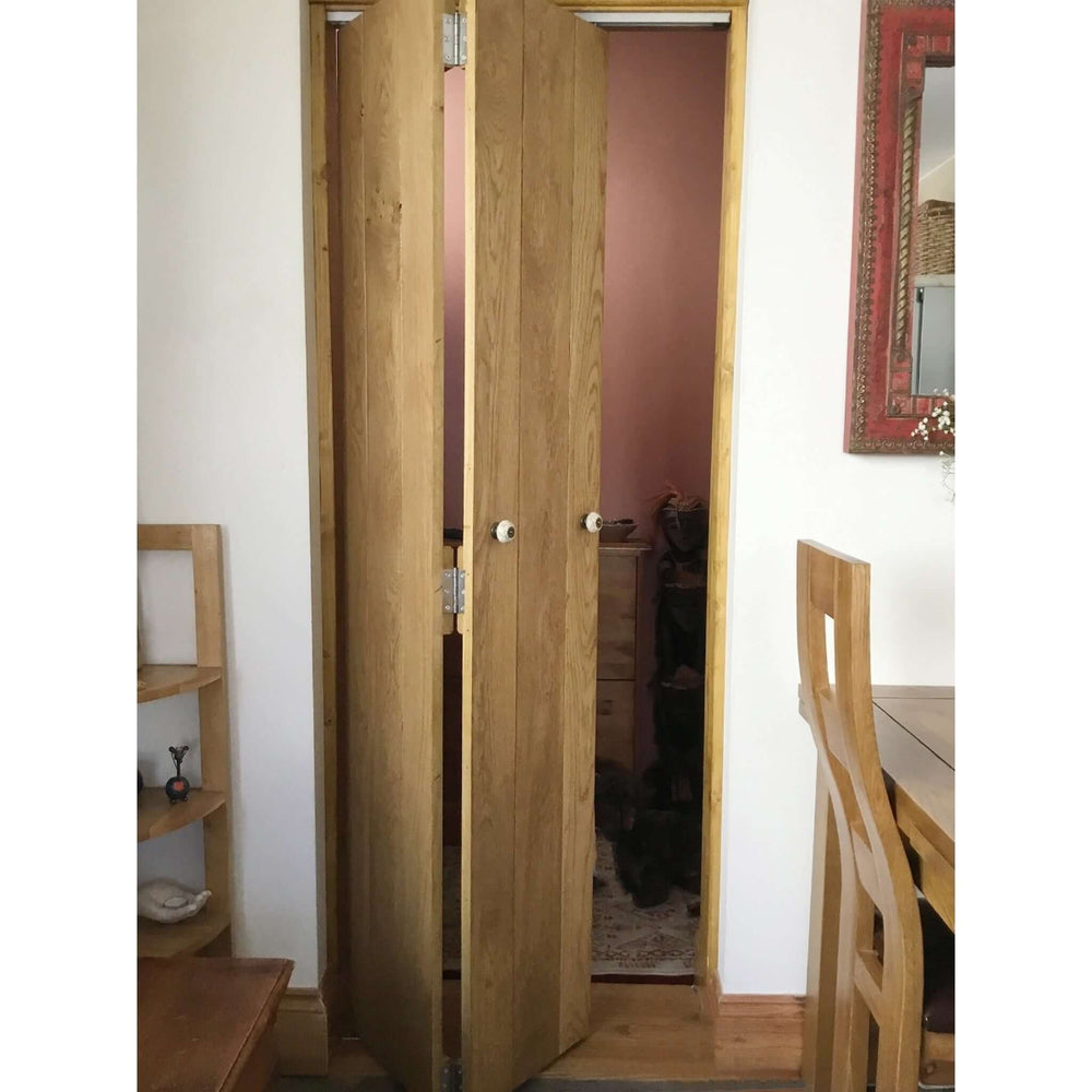 Lifestyle solid oak rustic bifold three-ledge V-groove cottage door folded in an interior